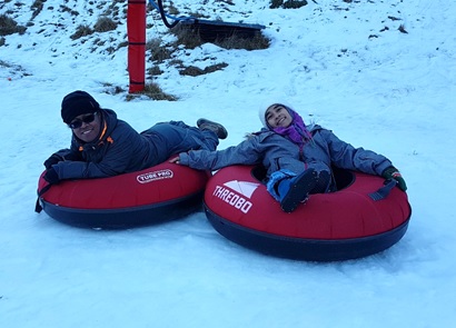 A man and woman with winter clothing are on the snow tire