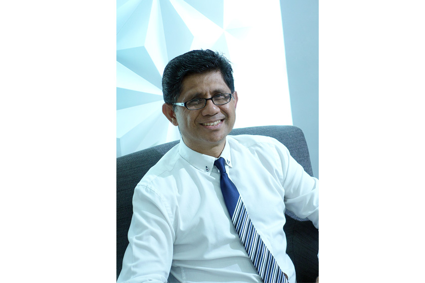 a man with glasses wearing white shirt and blue necktie sitting on the sofa