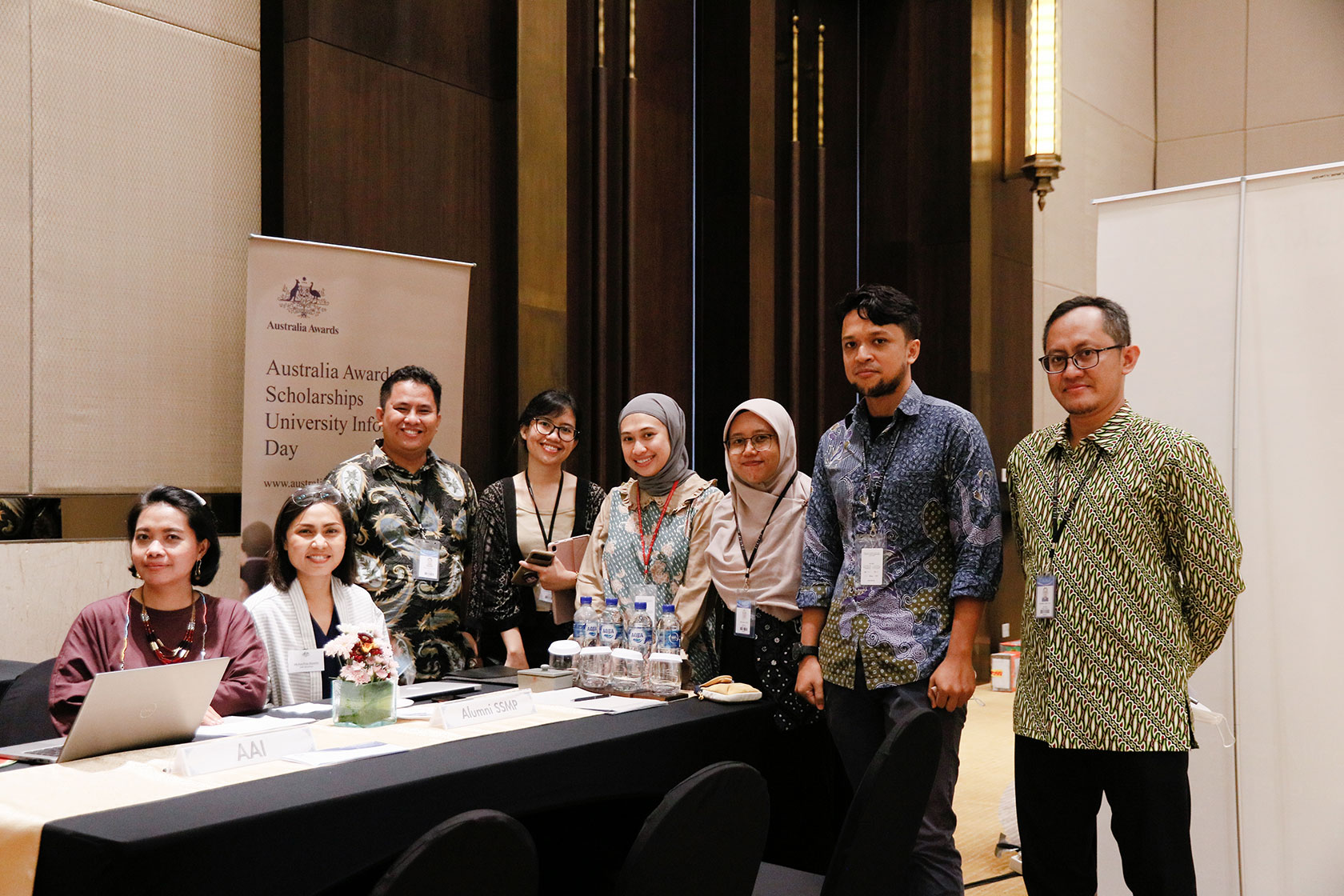 A group of people posing for pictures with Australia Awards Scholarships University Information Day standing banner in the background.